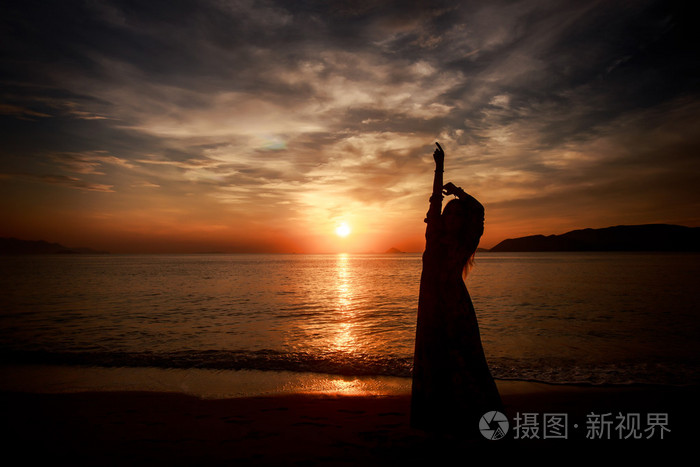 苗条的女孩,在这么长时间对海上日出的剪影