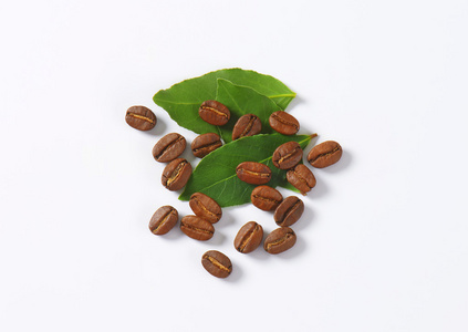 烘焙过的咖啡豆，绿色的叶子