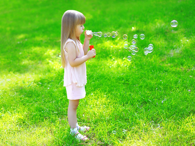 夏天，孩子站在草地上吹肥皂泡