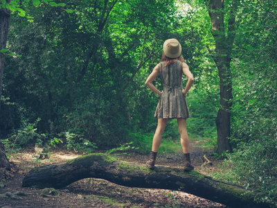 戴着帽子在森林中的日志上的女人