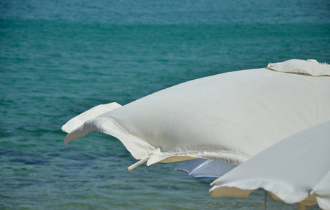 白色的阳伞和海在刮风的日子