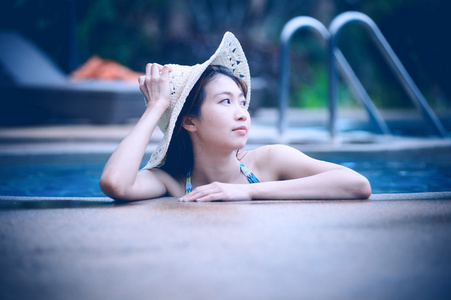 亚洲漂亮女人在享受游泳池的帽子