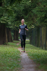 女跑步运动员贯穿春天公园路