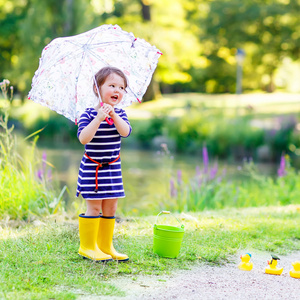 可爱的孩子的小姑娘在黄雨中夏公园