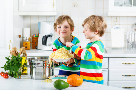 两个小家伙在国内的厨房里吃意大利面条的男孩