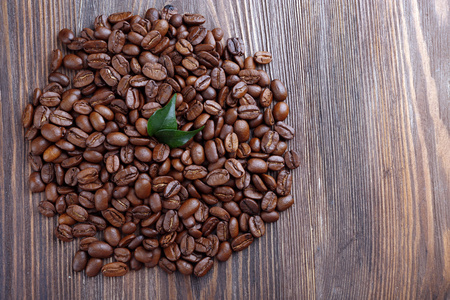 咖啡豆与叶木制的桌子上关闭