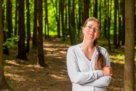 年轻的体贴的女子戴着眼镜在森林里的肖像