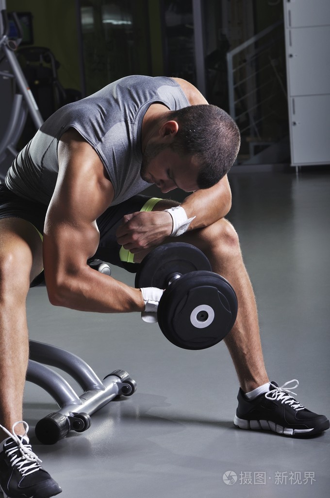 在坐姿与哑铃锻炼肱二头肌英俊肌肉男模特