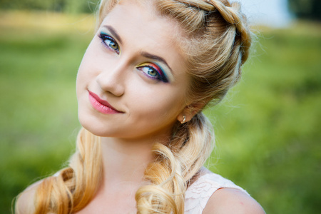 可爱的年轻漂亮金发姑娘与彩色化妆特写肖像。夏天外面