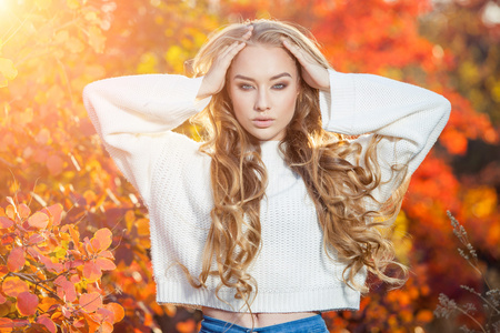 美丽的年轻女子，卷发的背景下，红色和黄色的秋天叶子