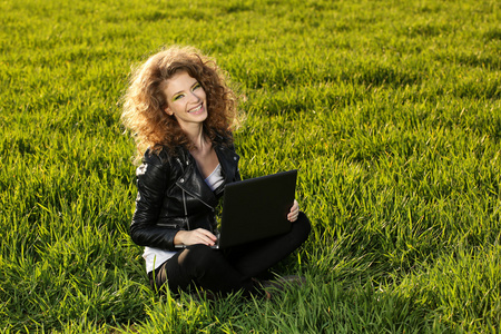 美女与笔记本电脑在绿色的田野