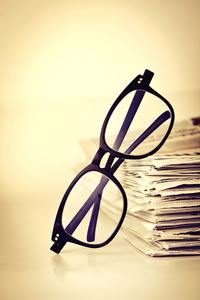 阅读眼镜与堆叠的报纸背景，业务