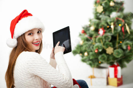 圣诞树上坐着一个拿着平板电脑的女人