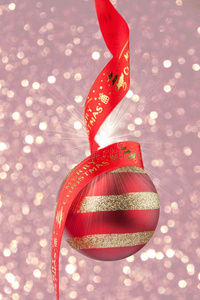 彩色纸屑背景上带红色丝带的圣诞饰品