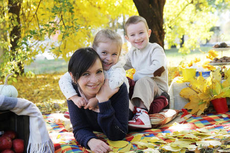 快乐的孩子们在秋树下拥抱他们的母亲