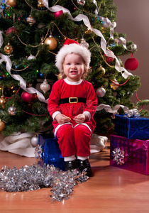 圣诞老人服装的女婴在圣诞树附近
