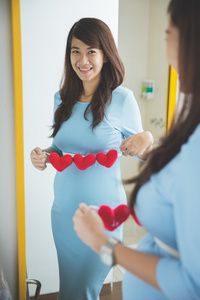 亚洲孕妇的心脏形状配件在她肚子上