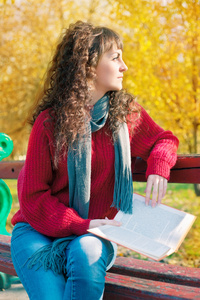 秋天的公园里看书的年轻女人