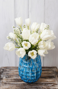 蓝色陶瓷花瓶里的白色郁金香花束