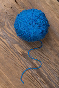 木制表面的蓝色针织纱球