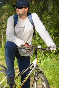 英俊的男人在乡下骑自行车