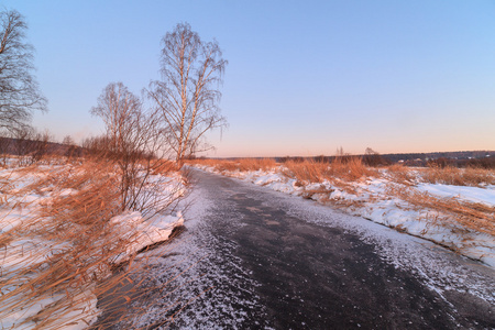 在寒冷的早晨日出冰冻的小河冰封的冬湖岸边的树木树木在冬天冰雪覆盖