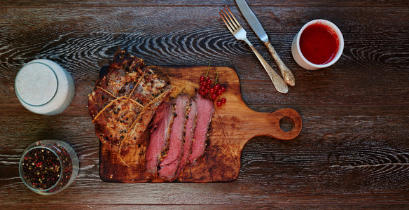 桌子上有一块木板, 厨师在上面把一块肉切成两半