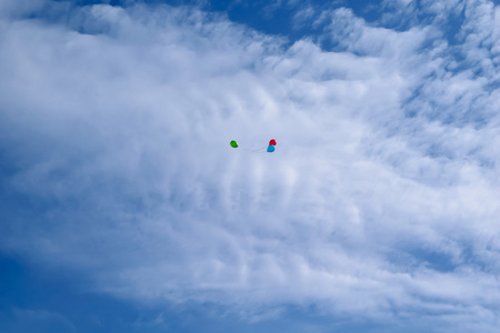 三个五颜六色的气球在蓝天上随云飞舞