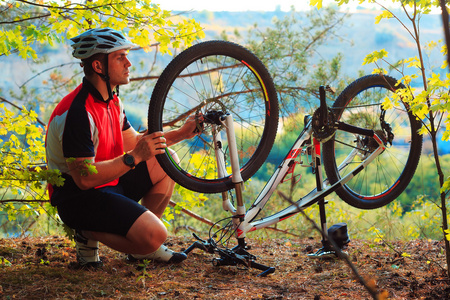 男子自行车修理自行车在树林里