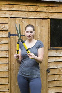 带花园修剪器的年轻妇女在庭院图片