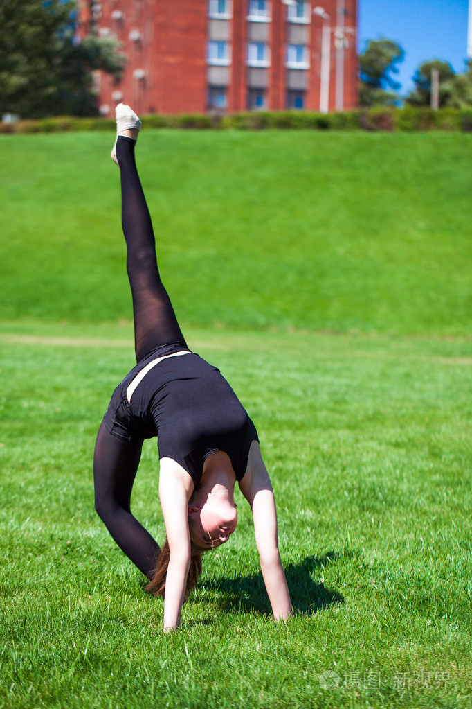 年轻的体操运动员在阳光明媚的日子的草地上