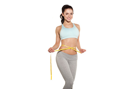运动女孩测量她的腰，在健身房里，锻炼腹部肌肉训练减肥