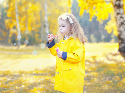 小女孩儿童吹肥皂泡在阳光明媚的秋日公园
