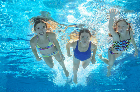 家庭游泳在游泳池或海洋水下，快乐积极的母亲和儿童有在水里，孩子们运动家庭度假的乐趣