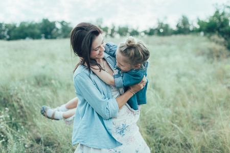 年轻的母亲和女儿上绿草背景