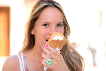 年轻快乐的女人，吃冰激淋室外的肖像