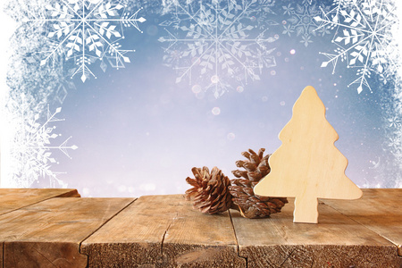 木制装饰圣诞树和松果上木桌和圣诞节节日景灯和雪花覆盖的抽象形象