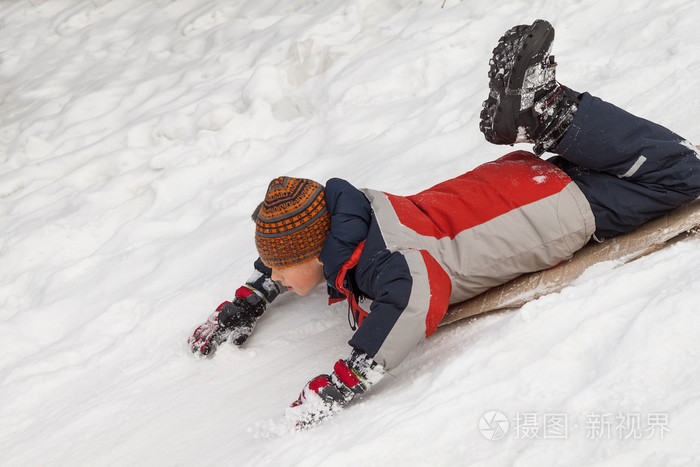 冬天的乐趣雪橇在冬天的时候。享受着雪橇的年轻男孩骑在一个美丽的白雪皑皑的冬季公园