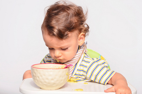 婴儿用勺子吃食物，蹒跚学步的孩子吃得乱七八糟，越来越多