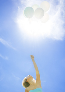 年轻的女孩，抱着太阳的背景上的气球