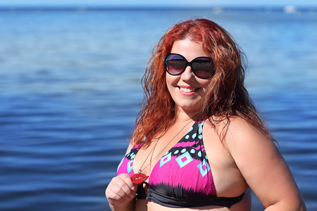 红发女人在海滩上休息的太阳镜