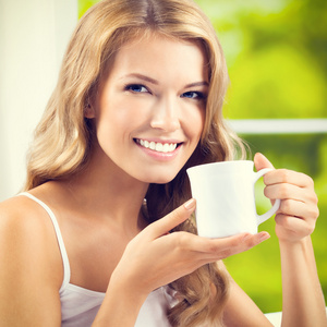 年轻女子在家里喝咖啡或茶，