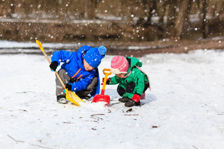 小男孩和女孩在冬天挖雪