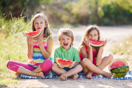 三个快乐微笑儿童吃西瓜在公园