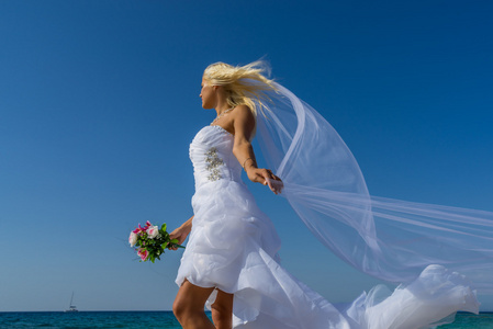 婚礼上的年轻新娘在海滩上玩得开心