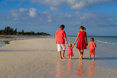 年轻的家庭，两个孩子在沙滩上散步
