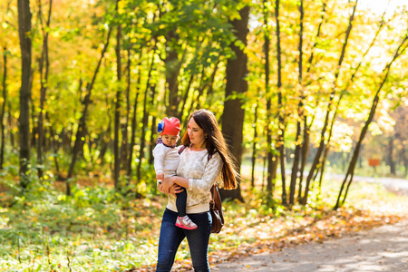 年轻的母亲与她的孩子在秋天的公园散步
