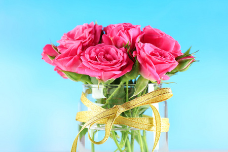 美丽的玫瑰,插在花瓶里在明亮的背景上照片