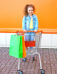 快乐的微笑孩子在手拉车与彩色购物袋