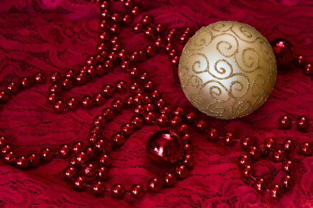 红色背景配件上的圣诞装饰品。黄金球玩具与明亮的花边